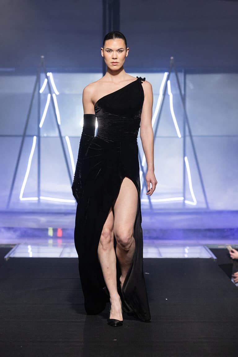 A model walks the On Aura Tout Vu couture runway wearing a sparkling ebroidered velvet dress and gloves