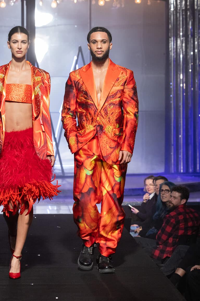 A male model walk on aura tout vu show wearing red orange custom print tuxedo