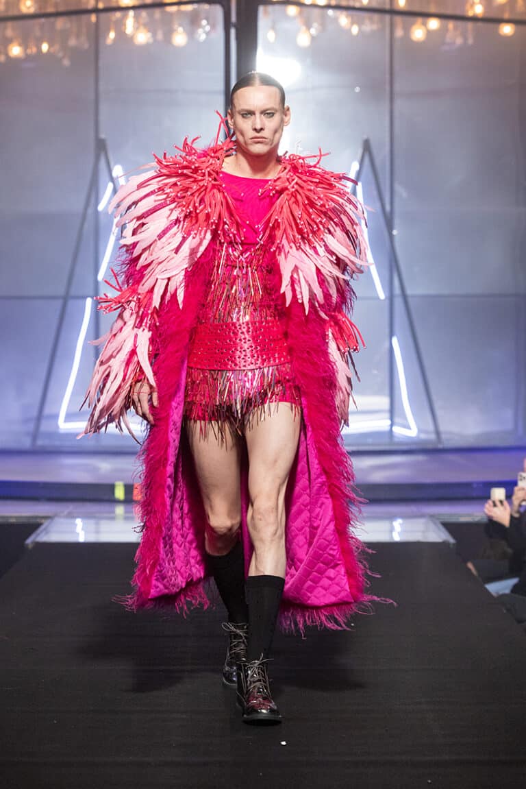 A male model walk on aura tout vu show wearing pink bodysuit and pink fathers coat