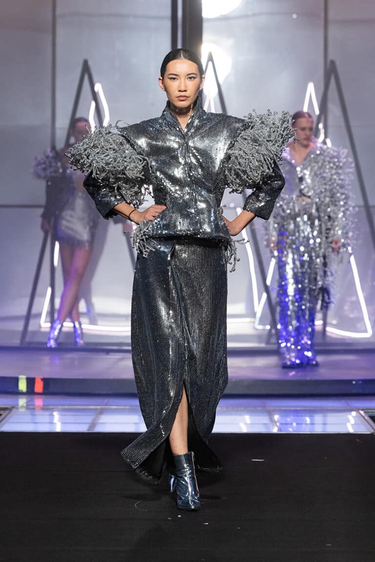 a model walking in a silver jacket embroydery and silver skirt.