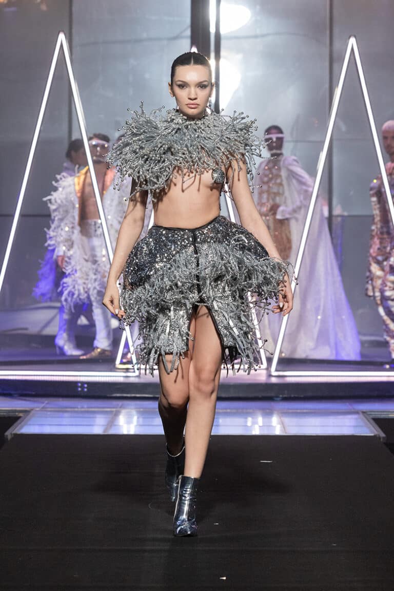 a model walking in silver top bolero and fringes silver dress