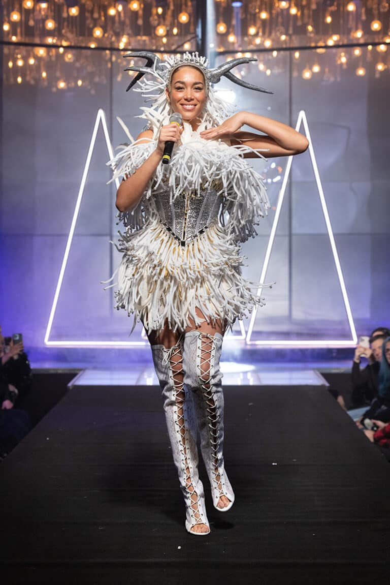 a model walking and singing at the on aura tout vu show wearing white corset and hornes