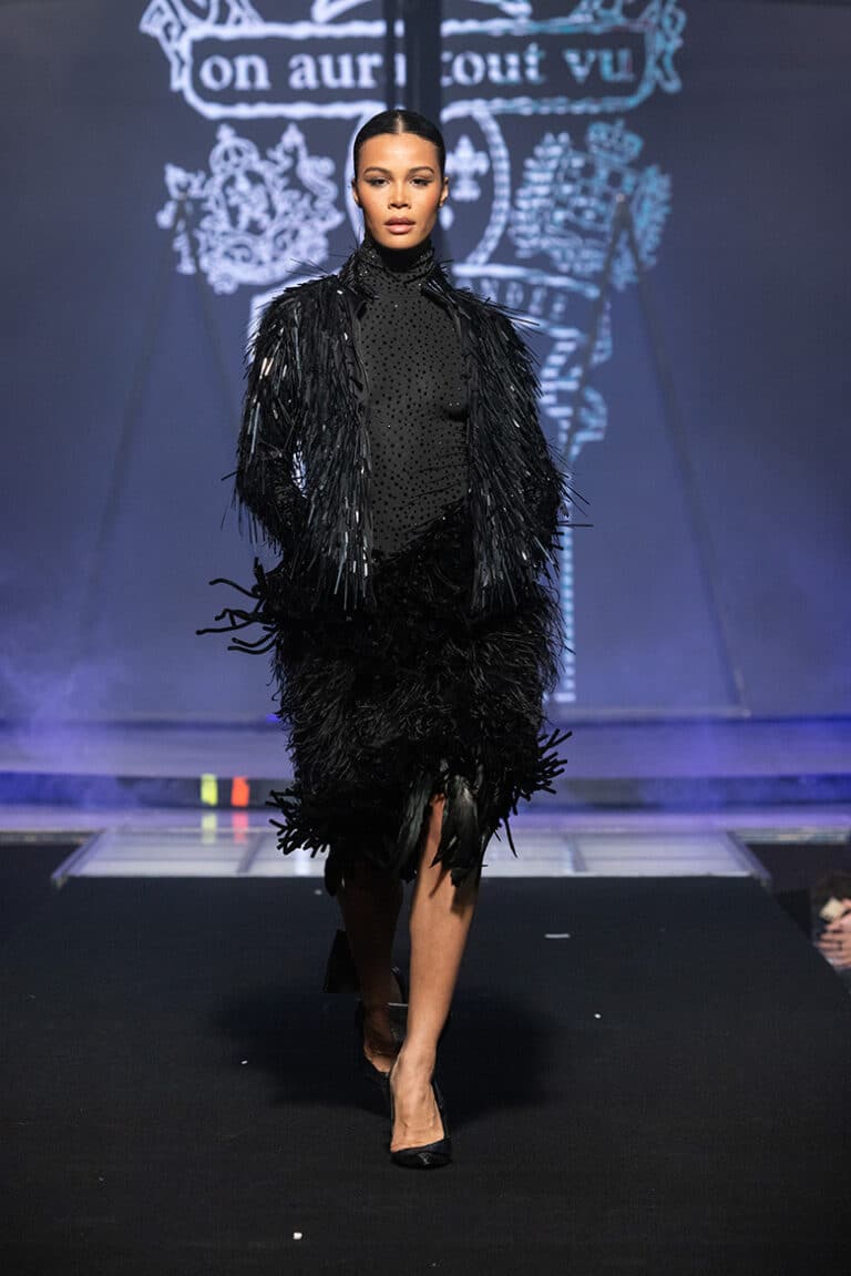 A male model walk on aura tout vu show wearing black embroidered dress black jacket embroidered with sequins.